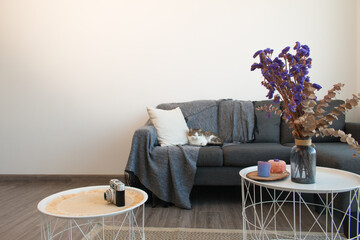 Decoración minimalista al estilo nórdico con naturaleza muerta y flores sobre mesas y sofá