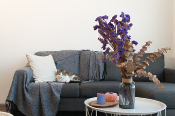 Decoración minimalista al estilo nórdico con naturaleza muerta y flores sobre mesas y sofá