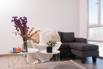 Decoración minimalista al estilo nórdico con naturaleza muerta y flores sobre mesas y sofá