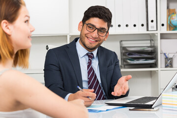 Successful businessman in glasses talking to female colleague in office