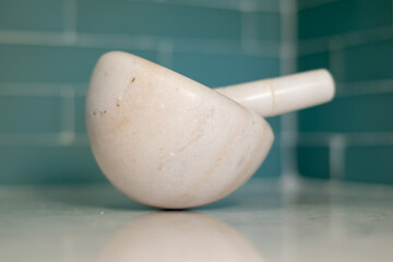 mortar and pestle set on a granite countertop with blue glass tile in background