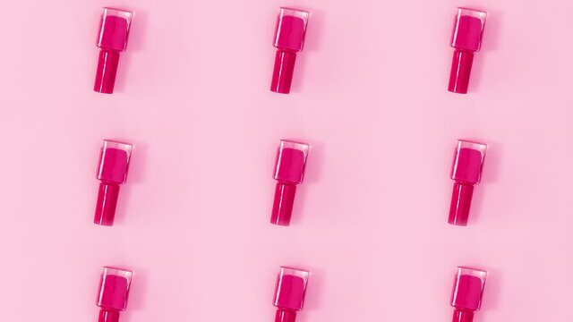 Beauty concept pattern made of nail polishes bottles in same color rotate on bright pink theme. Stop motion