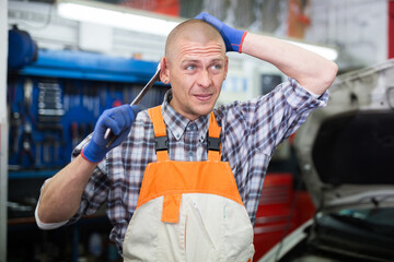 Portrait of professional man car mechanician standing near repairable car in auto repair shop
