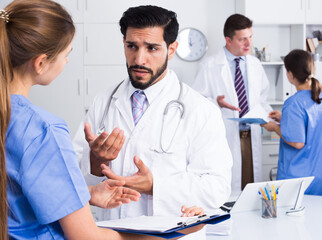 Doctor giving his younger female colleague piece of advice concerning diagnosis
