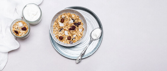Granola with chia seeds, coconut, dry berries and yogurt in bowls on grey background, copy space. Concept of healthy breakfast menu	