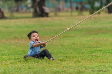 mixed race boy have fun playing rope pulling in park during summer