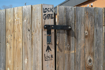Hand written instructions where to lock a gate on an old weathered fence