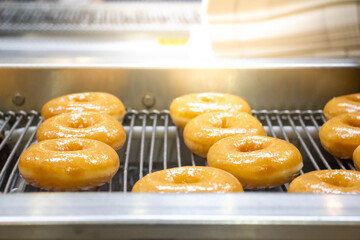 doughnuts or donut on conveyor belt in factory, a type of fried dough confectionery or dessert food