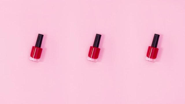 Three nail polishes bottles rotate on pastel pink background. Stop motion