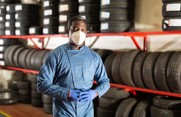 Fototapeta na wymiar Portrait of a auto mechanic in protective mask in front of car tires