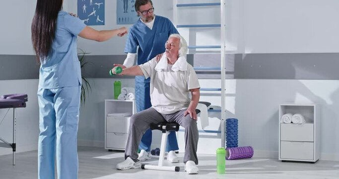 Male and female doctors showing rehabilitation exercise to elderly patient