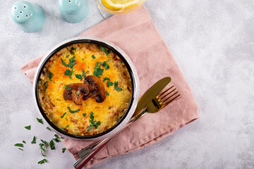 Julienne with potatoes and mushrooms in a baking dish on a light background, top view. Traditional French dish