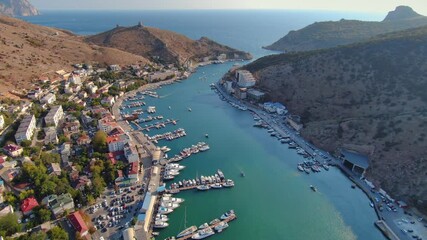 Aerial above Balaklava Bay Crimea Sevastopol, ruins of ancient Genoese fortress. Yachts boats ships sail. Resort paradise city embankment, tourist travel attraction. Seascape. Horizon. Golden hour