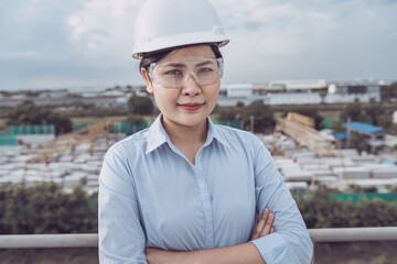 Female Civil Engineer in Safety Hard Hat Standing Against With Construction Site Background. Portrait of Professional Construction Engineer During Working at Building Project Site. Job Occupation