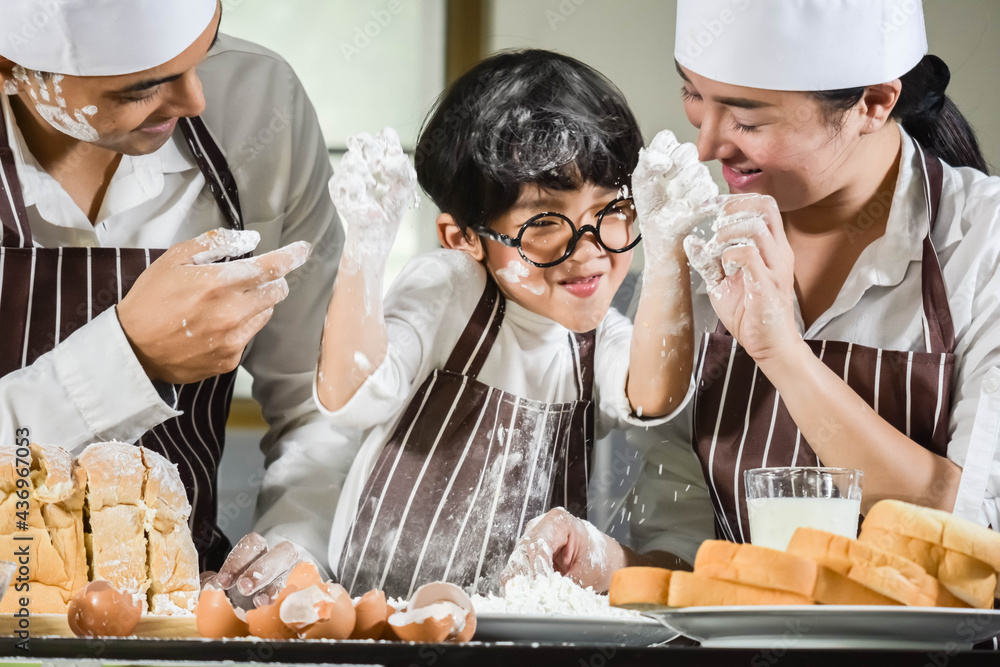 Wall mural Asian Boy wear glasses cooking with white flour Kneading bread dough teaches children practice baking ingredients bread, egg on tableware in kitchen lifestyle happy Learning life with family Fun