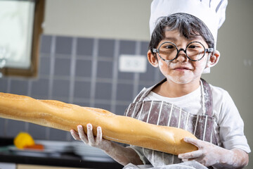 Asian Boy wear glasses cooking with white flour Kneading bread dough teaches children practice...