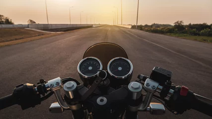 Zelfklevend Fotobehang Driver riding motorcycle on an asphalt road in highway at sunset, details of the steering bar. © Satawat