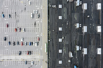 parking lot with parked cars and roof of shopping mall. abstract urban background. aerial top view.