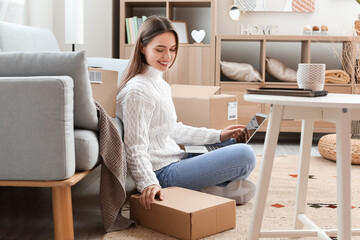 Young woman with parcel and laptop at home