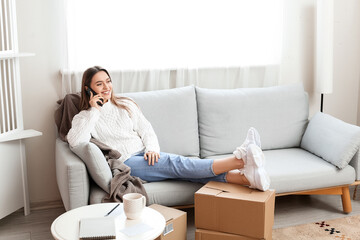 Young woman talking by mobile phone at home