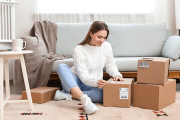 Young woman preparing parcel for client at home