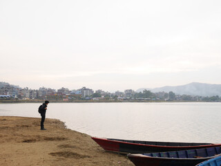 Fototapeta na wymiar Viewpoint and wooden canoe boat of nepali floating in Phewa Tal or Fewa lake wait service Nepalese people and foreign travelers rowing travel relax visit tour at Pokhara of Gandaki Pradesh in Nepal