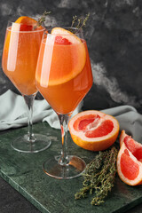 Glasses of tasty grapefruit cocktail with thyme on dark background