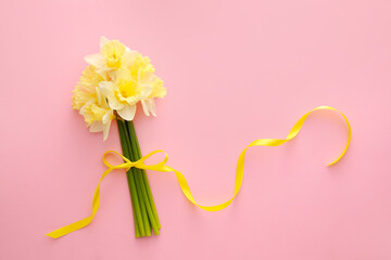 Beautiful daffodils with ribbon on color background