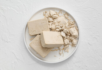 Plate with fresh yeast on light background
