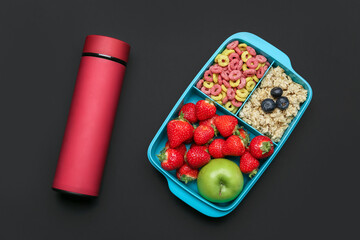 Lunchbox with tasty food and thermos on dark background
