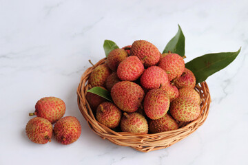 Bunch of fresh ripe lychee fruit with green leaves on white background. Exotic or tropical litchi fruit. Lichi. Copy space.