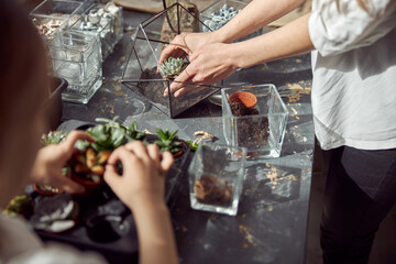 caucasian confident happy florist is working with her young daughter and making composition from...