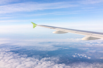 View from the airplane window at a beautiful blue sunrise and the airplane wing above the clouds.