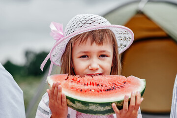 Portrait of little girl at picnic. Child eating watermelon in the meadow.