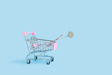 dental tools mirror and probe in shop in cart basket trolley on blue background. medical supplies....