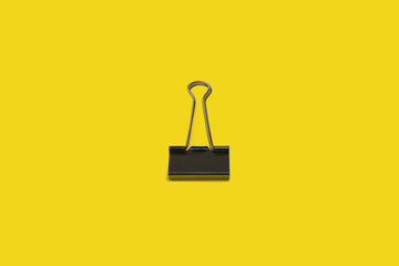 black paper clip on a yellow surface