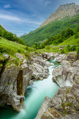 Long exposure of flowing water in Verzasca River at Lavertezzo - clear and turquoise water stream and rocks in Ticino - Valle Verzasca - Valley in Tessin - Travel destination in Switzerland