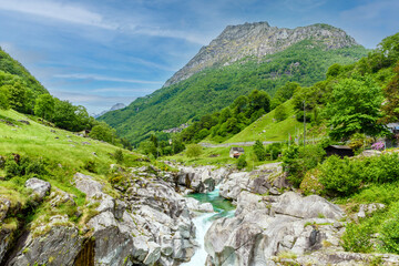 Fototapeta na wymiar Long exposure of flowing water in Verzasca River at Lavertezzo - clear and turquoise water stream and rocks in Ticino - Valle Verzasca - Valley in Tessin - Travel destination in Switzerland