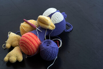 Balls of yarn, amigurumi doll elements, crochet hook.