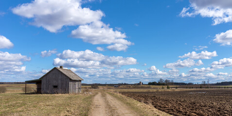 An old abandoned small wooden house in the field blue sky white clouds, barn or scary concept.