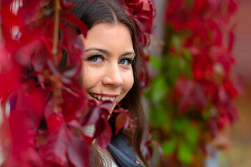 young smilling woman upon a wall of red ivy leaves