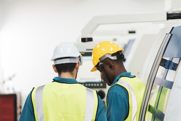 Caucasian and African worker discuss together in factory production line machine. Concept of multi ethnic group of people and diversity with copy space.