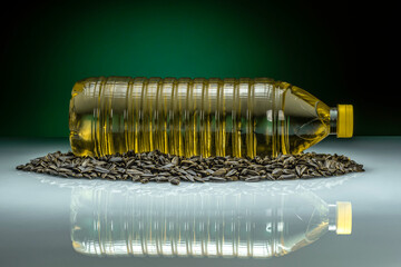 Cooking sunflower oil plastic bottle placed on sunflower seeds isolated on reflective glass and...