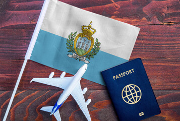 Flag of San Marino with passport and toy airplane on wooden background. Flight travel concept
