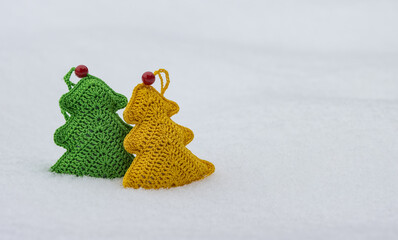 Green and yellow knitted toy on white snow.