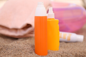 Lotion and sunscreen stand on sand on beach