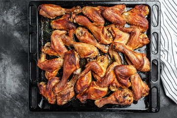 Oven baked chicken pieces wings and legs on baking tray, Homemade food tasty and hearty meal. Food recipe background. Close up