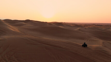 Fototapeta na wymiar AERIAL. ATV travelling in sand desert.