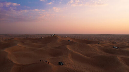 AERIAL. Column of white cars travelling in sand desert.