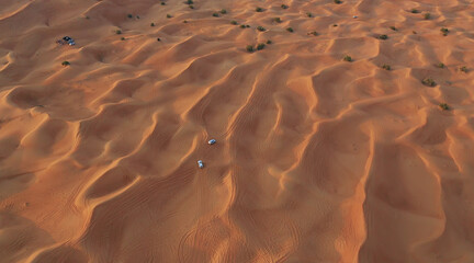 Fototapeta na wymiar AERIAL. Column of white cars travelling in sand desert.